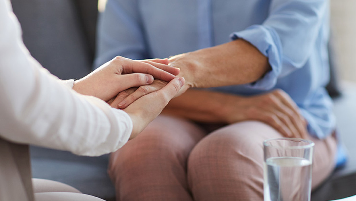 Foto de dos personas dándose la mano en una consulta de psicología