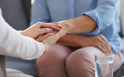 Foto de dos personas dándose la mano en una consulta de psicología
