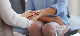 Foto de dos personas dándose la mano en una consulta de psicología