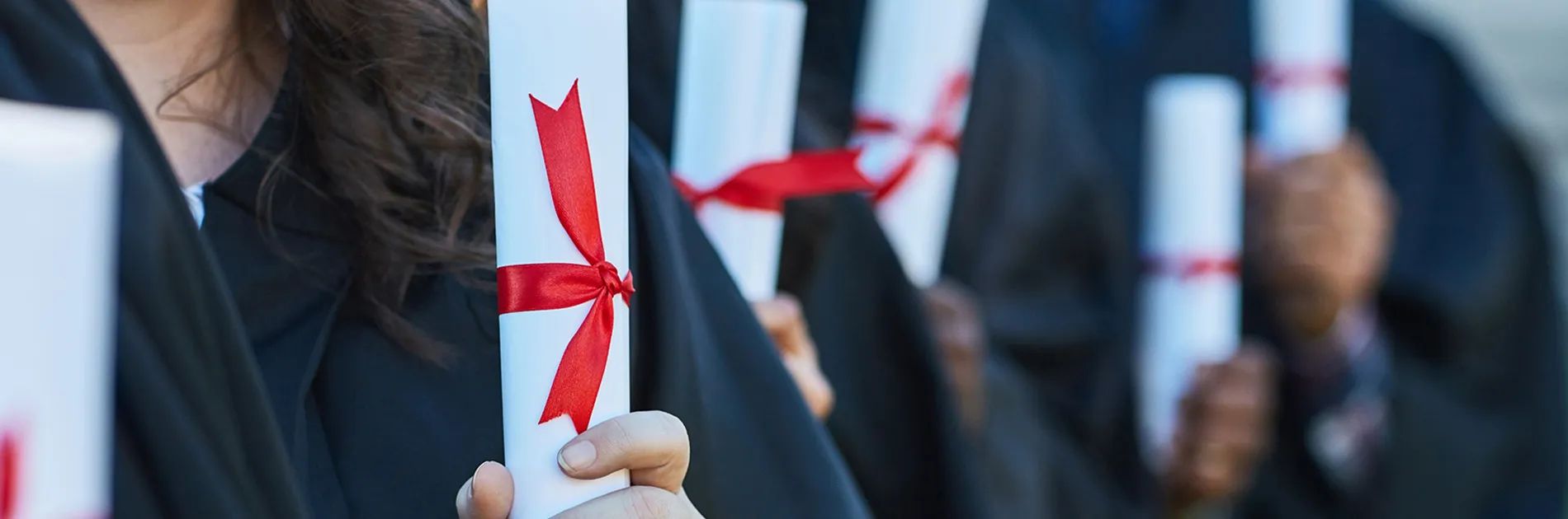 Personas graduadas sujetando el título en representación de qué es una mención en la universidad
